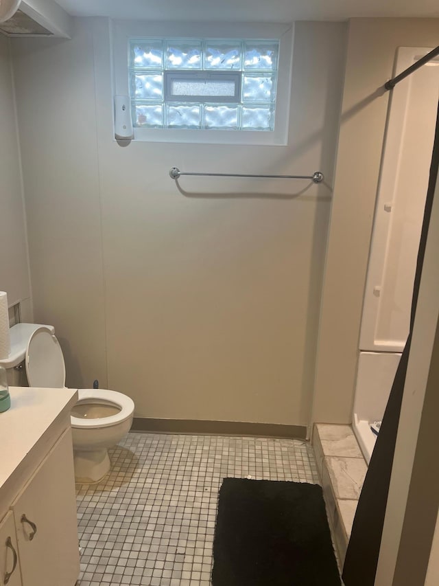 bathroom with a shower stall, vanity, tile patterned flooring, toilet, and baseboards