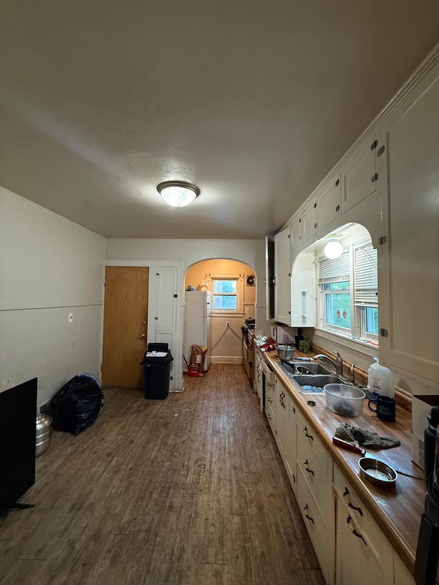608 7th Ave S, Saint Cloud, MN 56301 - kitchen featuring arched walkways, freestanding refrigerator, dark wood finished floors, white cabinetry, and a sink