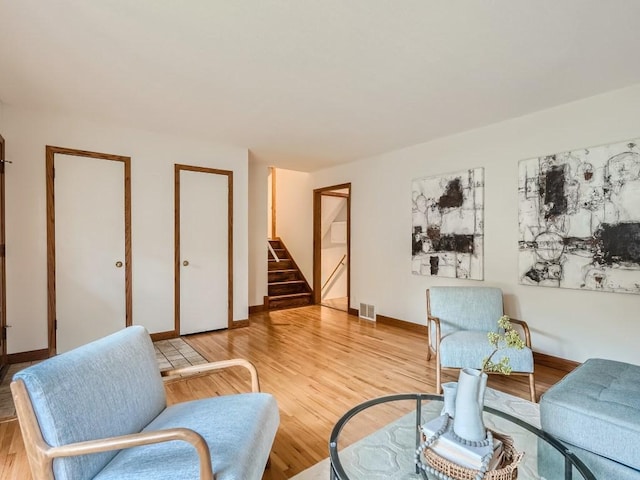 living room featuring stairs, baseboards, visible vents, and light wood-style flooring