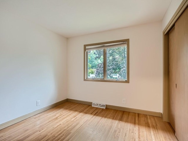 unfurnished bedroom with baseboards, visible vents, light wood finished floors, and a closet