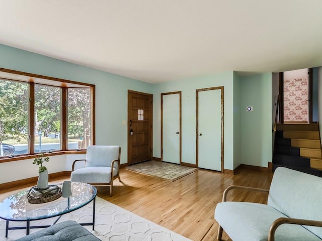 living room featuring light wood-style floors, baseboards, and stairs