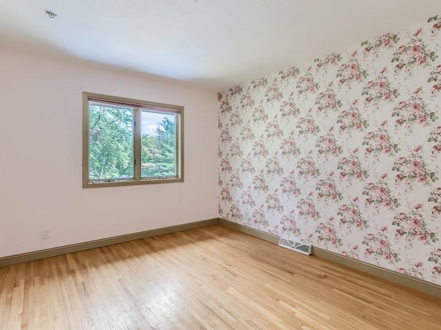 empty room featuring baseboards, visible vents, and light wood-style flooring