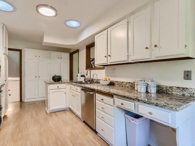 kitchen with stainless steel dishwasher, a sink, white cabinetry, and stone countertops