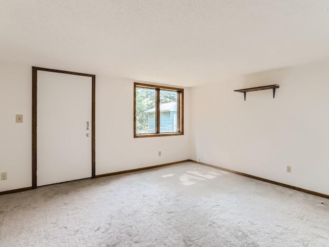 carpeted empty room featuring baseboards