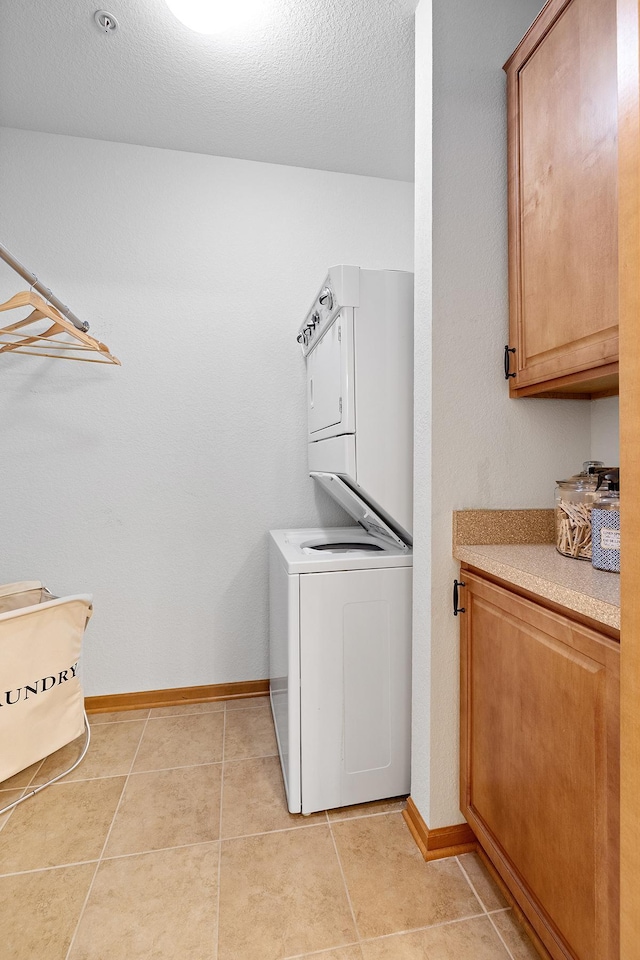 7100 Metro Blvd Unit 206, Edina, MN 55439 - laundry room with cabinet space, stacked washer / drying machine, a textured ceiling, baseboards, and light tile patterned floors