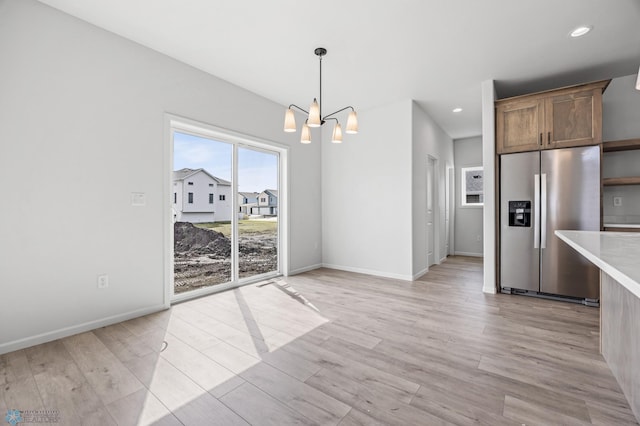 3187 Archer Pl S, Fargo, ND 58104 - kitchen with stainless steel fridge, light countertops, a chandelier, light wood-type flooring, and baseboards