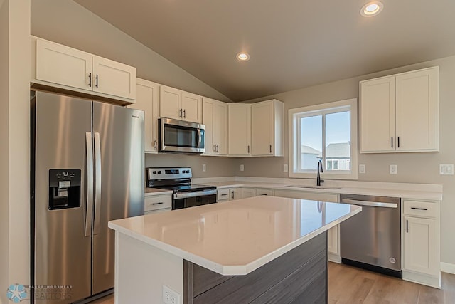kitchen with white cabinets, recessed lighting, vaulted ceiling, a sink, and stainless steel appliances