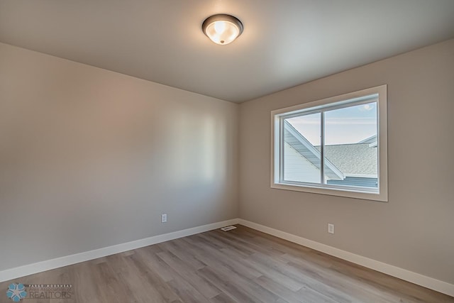 spare room featuring visible vents, baseboards, and wood finished floors