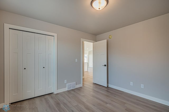 unfurnished bedroom featuring a closet, light wood-type flooring, visible vents, and baseboards