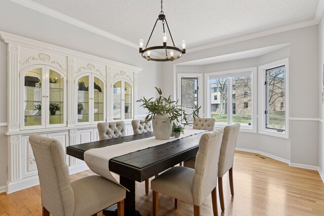 7604 Delaney Blvd, Edina, MN 55439 - dining space with a chandelier, baseboards, light wood-type flooring, a textured ceiling, and crown molding