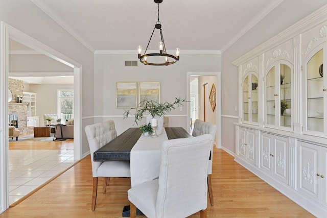 7604 Delaney Blvd, Edina, MN 55439 - dining room featuring a chandelier, ornamental molding, light wood finished floors, and a stone fireplace