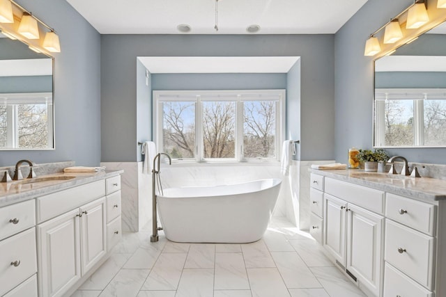 7604 Delaney Blvd, Edina, MN 55439 - full bathroom with two vanities, marble look tiles, a freestanding tub, and a wainscoted wall