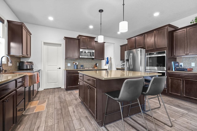 5836 Radford Ave NE, Otsego, MN 55374 - kitchen featuring a sink, a kitchen island, dark brown cabinetry, decorative backsplash, and appliances with stainless steel finishes