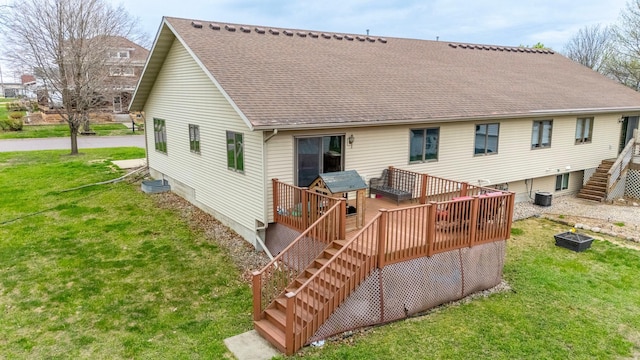rear view of property with stairway, a deck, a lawn, and roof with shingles