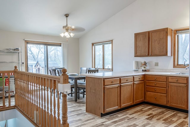 kitchen with a ceiling fan, vaulted ceiling, a peninsula, light countertops, and light wood-style flooring