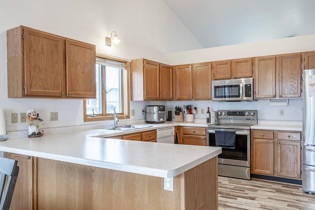 kitchen with appliances with stainless steel finishes, a sink, a peninsula, light countertops, and high vaulted ceiling