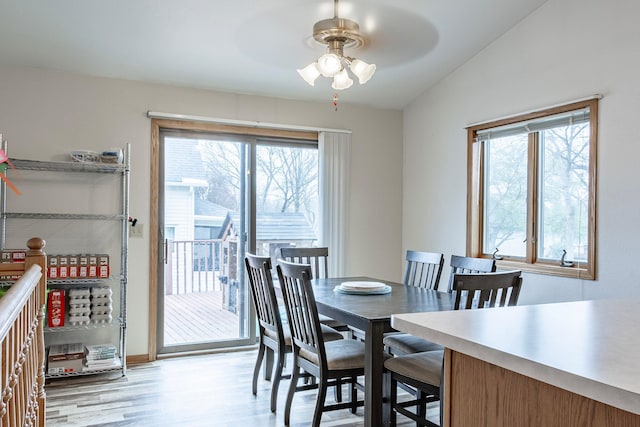 dining space featuring a ceiling fan, healthy amount of natural light, vaulted ceiling, and light wood-style floors