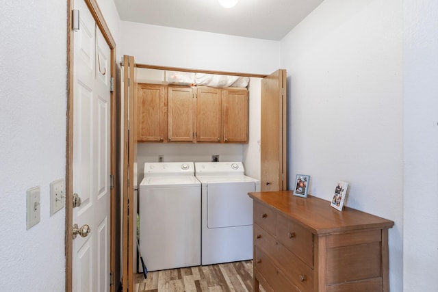 laundry room with washer and clothes dryer, cabinet space, and light wood finished floors