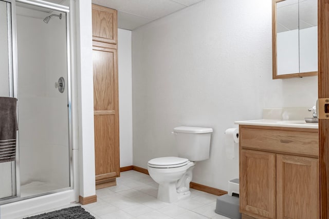 bathroom featuring a stall shower, baseboards, toilet, vanity, and tile patterned flooring
