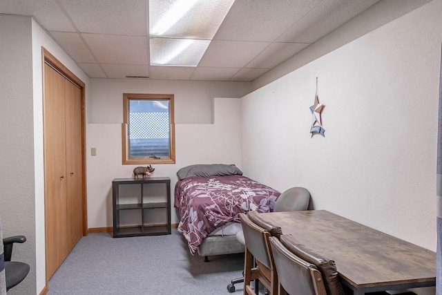 carpeted bedroom featuring a paneled ceiling and a closet