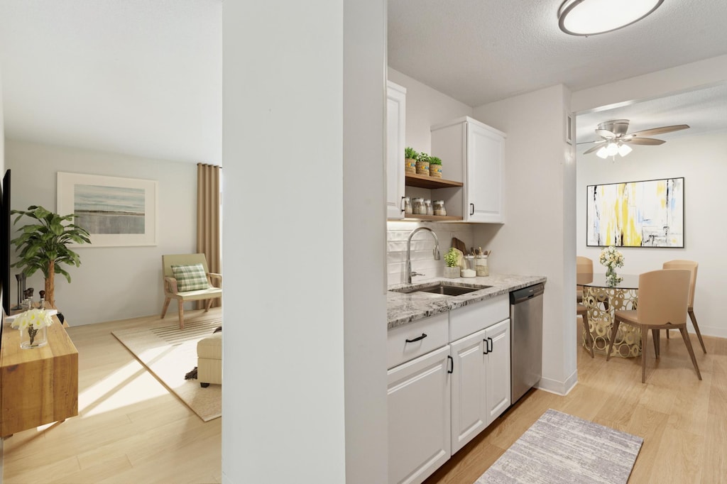 bar featuring ceiling fan, light wood-style floors, stainless steel dishwasher, and a sink