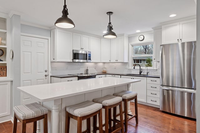 kitchen featuring ornamental molding, a sink, appliances with stainless steel finishes, and a breakfast bar