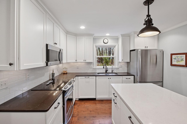 kitchen with a sink, white cabinets, ornamental molding, and stainless steel appliances