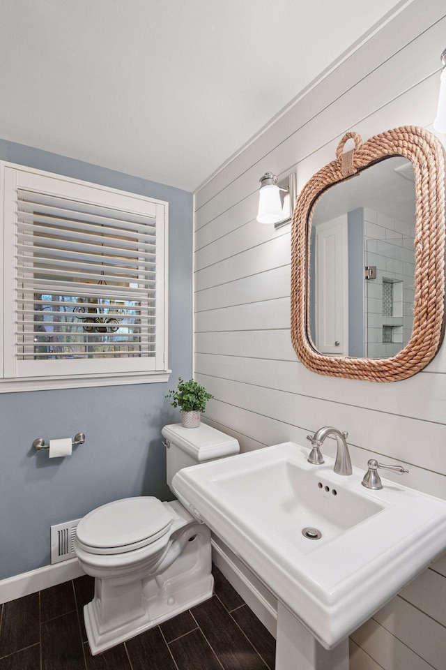 bathroom with visible vents, wood walls, toilet, baseboards, and wood finish floors