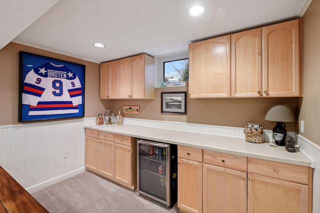 kitchen with beverage cooler, light countertops, wainscoting, and light brown cabinetry