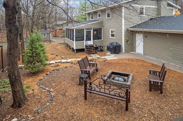 rear view of house with an outdoor structure, a fire pit, a patio, a sunroom, and a storage shed