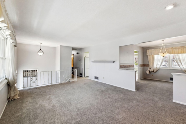 unfurnished living room with visible vents, carpet, and baseboards