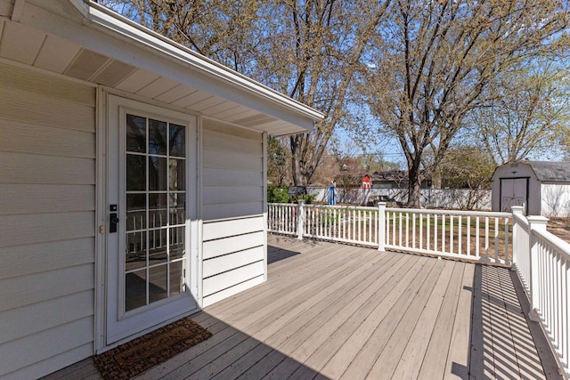 deck featuring a storage unit, fence, and an outbuilding