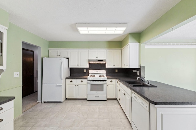 kitchen featuring a sink, dark countertops, under cabinet range hood, and white appliances