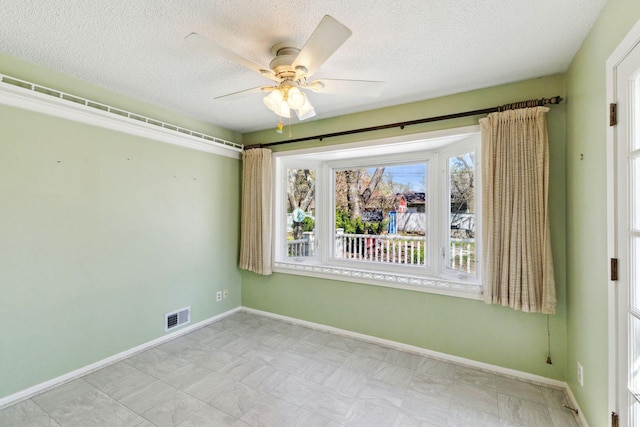 unfurnished room featuring a ceiling fan, baseboards, visible vents, and a textured ceiling
