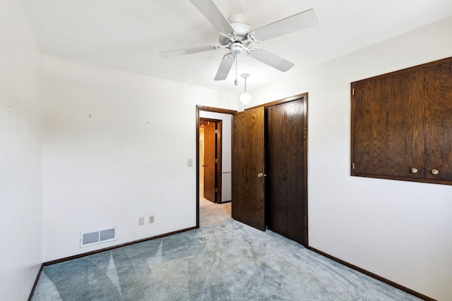 unfurnished bedroom with ceiling fan, light colored carpet, baseboards, visible vents, and a closet