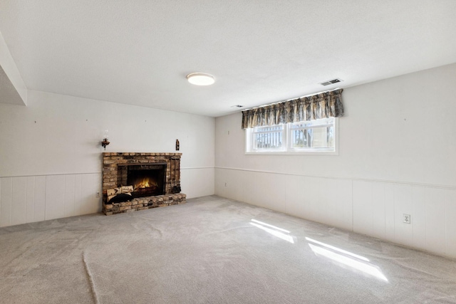 unfurnished living room featuring visible vents, carpet flooring, wainscoting, and a fireplace