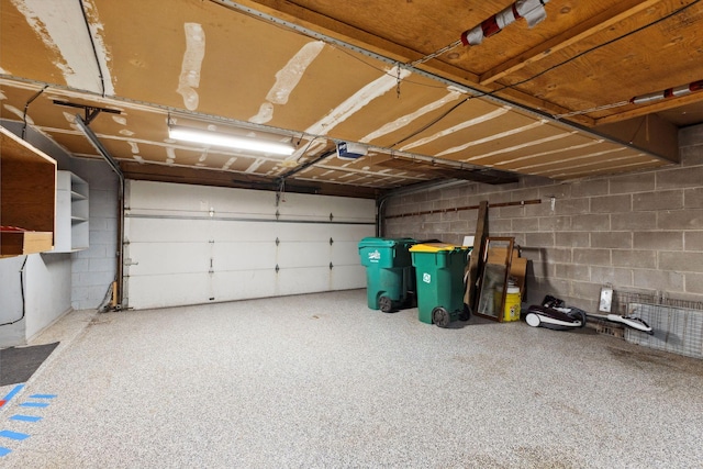 garage featuring concrete block wall and a garage door opener