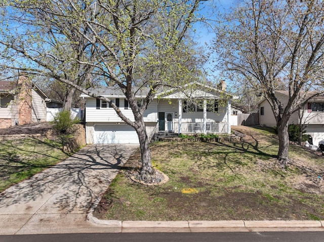 bi-level home featuring a garage, a porch, driveway, and a front yard
