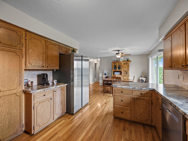 26635 Variolite St NW, Stanford Twp, MN 55070 - kitchen with appliances with stainless steel finishes, light wood-type flooring, a peninsula, a ceiling fan, and brown cabinets