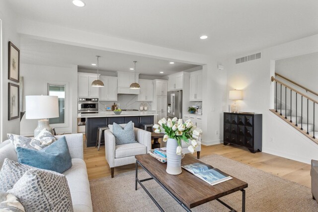 living area with baseboards, recessed lighting, light wood-style flooring, stairs, and visible vents