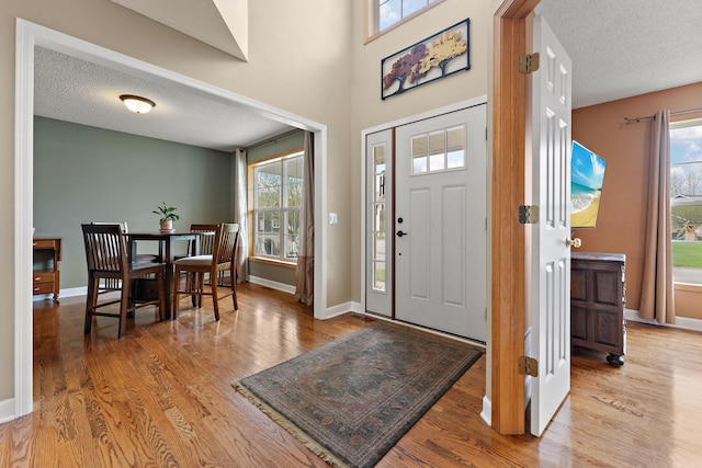 entrance foyer featuring baseboards, plenty of natural light, a textured ceiling, and wood finished floors
