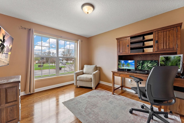 office space with a textured ceiling, baseboards, and light wood finished floors