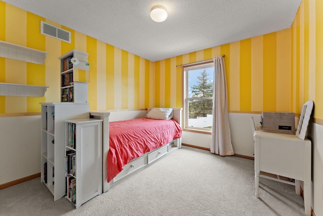carpeted bedroom featuring visible vents, a textured ceiling, baseboards, and wallpapered walls