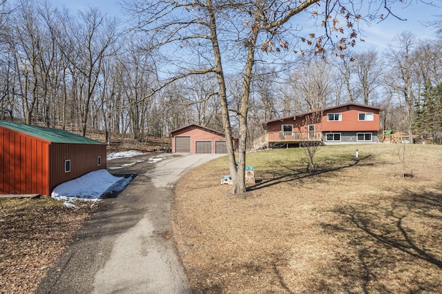 view of front facade featuring a front yard, driveway, an outbuilding, and a detached garage