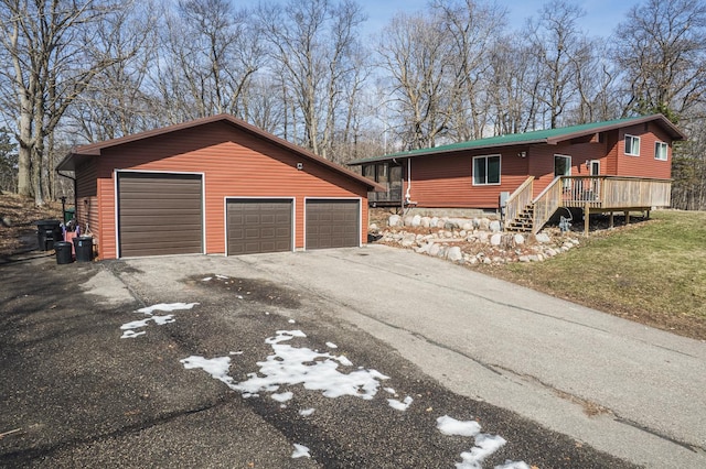 view of front of property featuring a wooden deck, a detached garage, and an outdoor structure