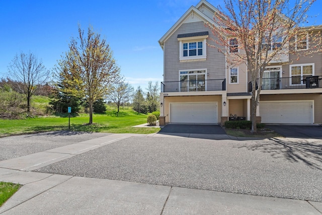 townhome / multi-family property with a front lawn, driveway, a garage, and a balcony