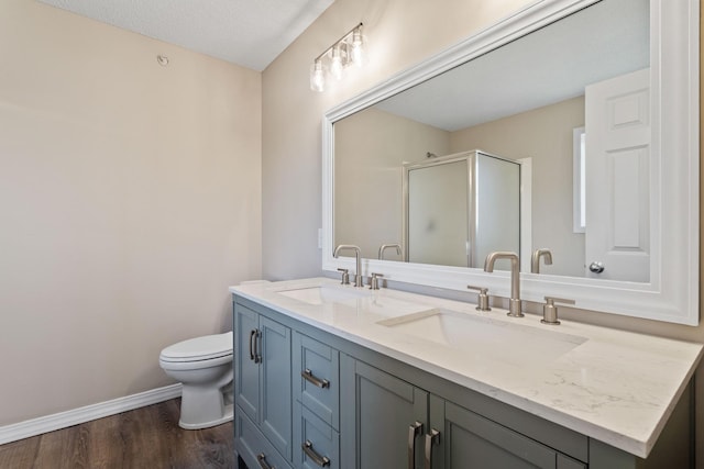 bathroom featuring a stall shower, double vanity, a sink, and wood finished floors