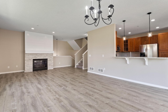 unfurnished living room with stairway, light wood-style flooring, recessed lighting, baseboards, and a chandelier