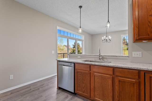 kitchen featuring dishwasher, a sink, brown cabinets, light wood-style flooring, and a textured ceiling