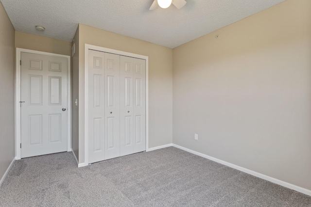 unfurnished bedroom featuring carpet floors, baseboards, a closet, a textured ceiling, and a ceiling fan